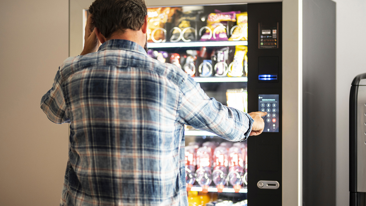 Hombre usando una máquina expendedora de alimentos y bebidas